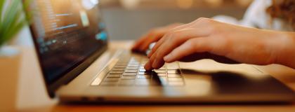Closeup of hands on a laptop.