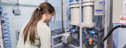 Person wearing a medical mask works in a water lab setting.