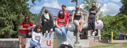 Students in masks sitting on the cannon.