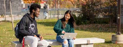 Two Students sitting on bench outside South Residence