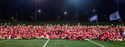 Orientation Volunteers (OVs) in a group on the football field after Pep Rally