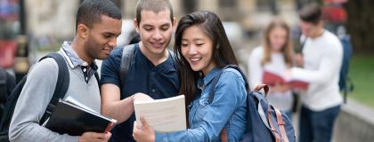 Group of international students looking at a book together.