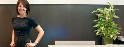 a person smiling, standing at a reception desk