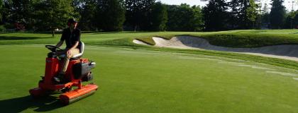 Person sits on a machine going over a golf course.