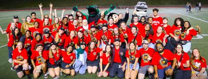 Image of a group of students grouped together on the Football Field wearing red t-shirts.