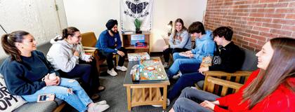Students talking and playing boardgame in the residence lounge