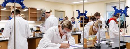 Group of students in Chem1040 lab wearing persona protective equipment and writing in notebooks