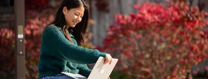Student sitting at a bench looking at a laptop