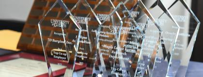 A table with a set of glass awards given by the University of Guelph and addressed to various top co-op employers