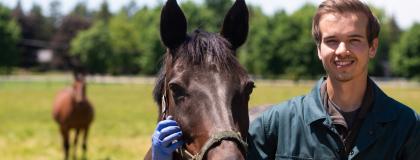 Person smiles beside a horse.