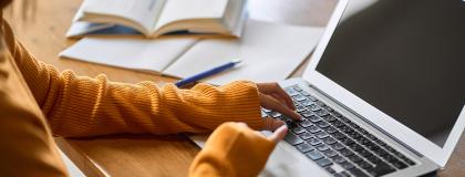 Closeup of students hands on a laptop.