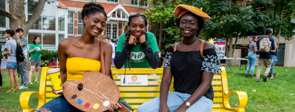 Students sitting on bench with art supplies