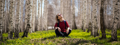 a student in the middle of a forest, looking up into the skyline